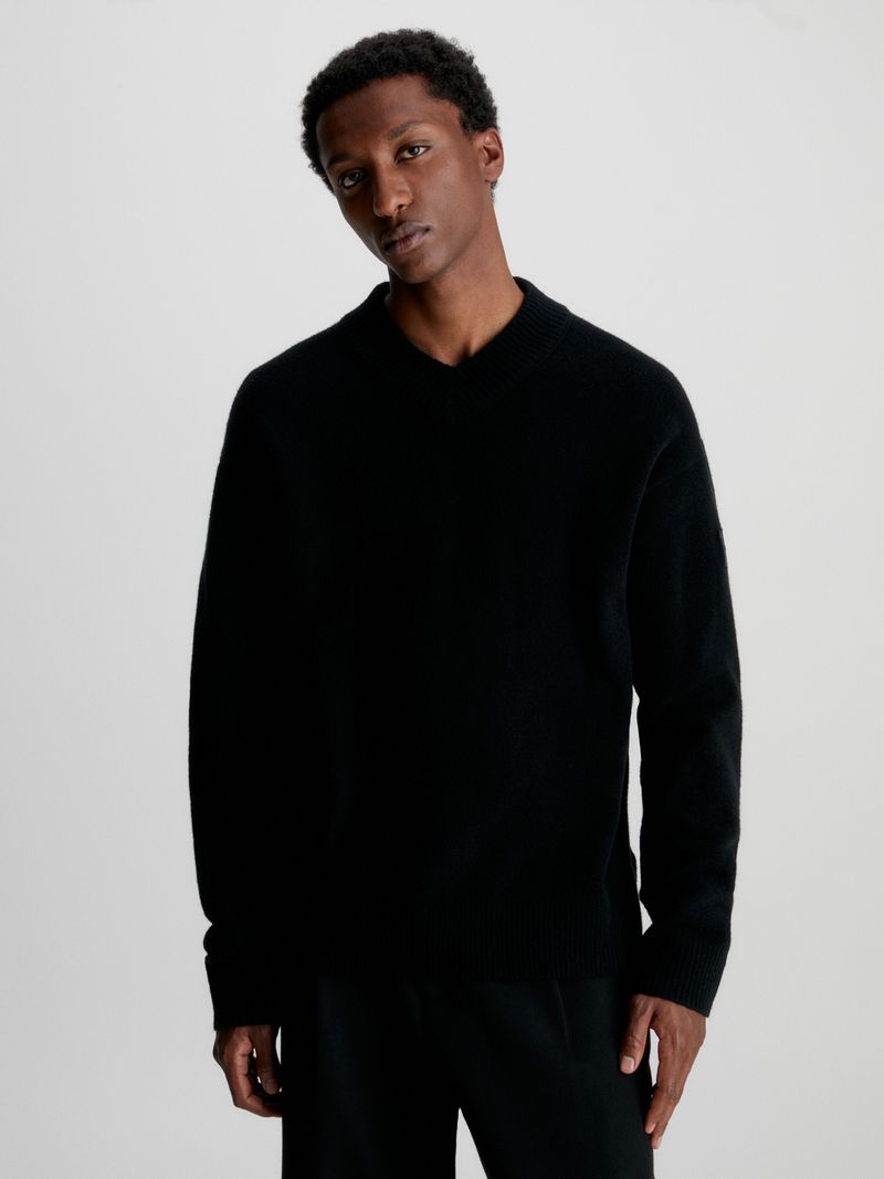Modelo-con-sweater-negro-de-cuello-en-V-Calvin-Klein-y-pantalones-oscuros