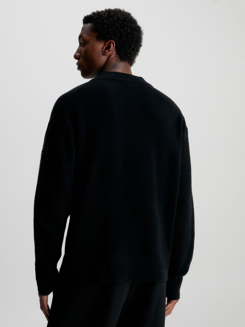Modelo-con-sweater-negro-de-cuello-en-V-Calvin-Klein-y-pantalones-oscuros