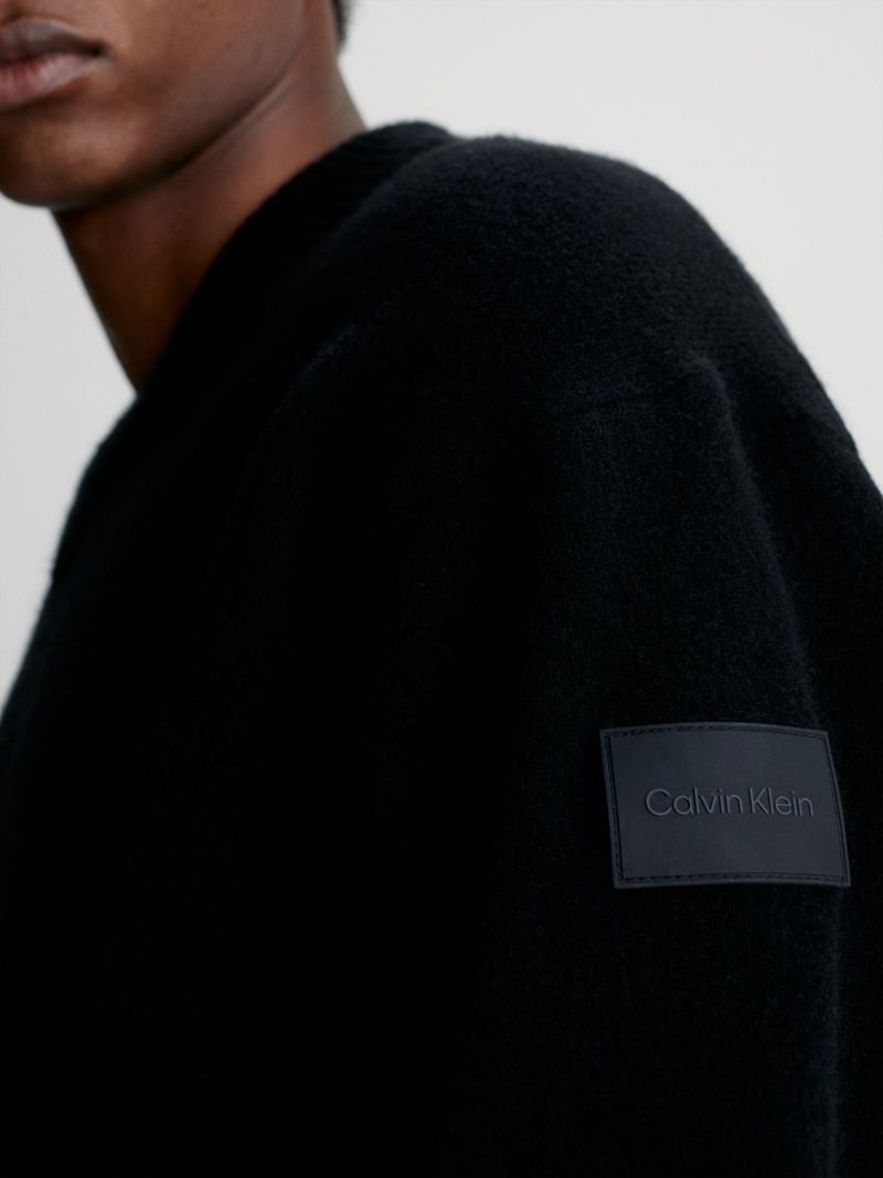 Modelo-con-sweater-negro-de-cuello-en-V-Calvin-Klein-y-pantalones-oscuros