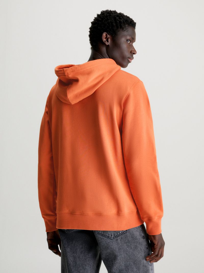 Modelo-con-poleron-naranja-Calvin-Klein-y-pantalones-negros