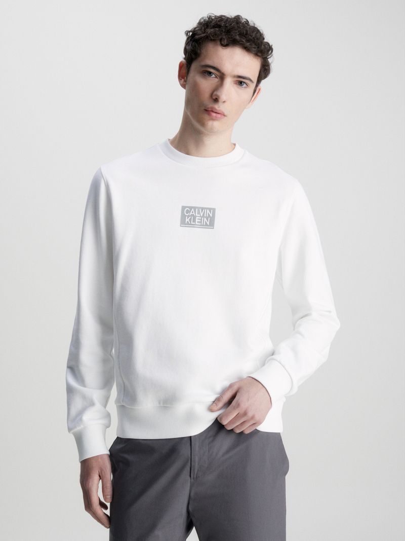 Hombre-con-poleron-blanco-Calvin-Klein-de-manga-larga-cuello-redondo-y-logo-en-el-pecho-combinado-con-pantalon-oscuro.