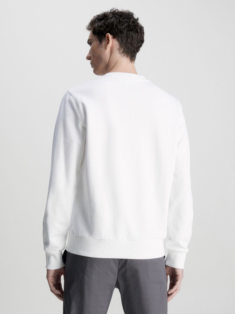 Hombre-con-poleron-blanco-Calvin-Klein-de-manga-larga-cuello-redondo-y-logo-en-el-pecho-combinado-con-pantalon-oscuro.