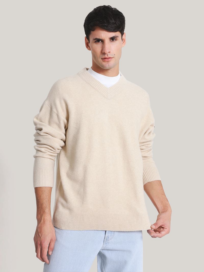 Modelo-con-sweater-beige-Calvin-Klein-de-cuello-en-V-y-jeans-claros