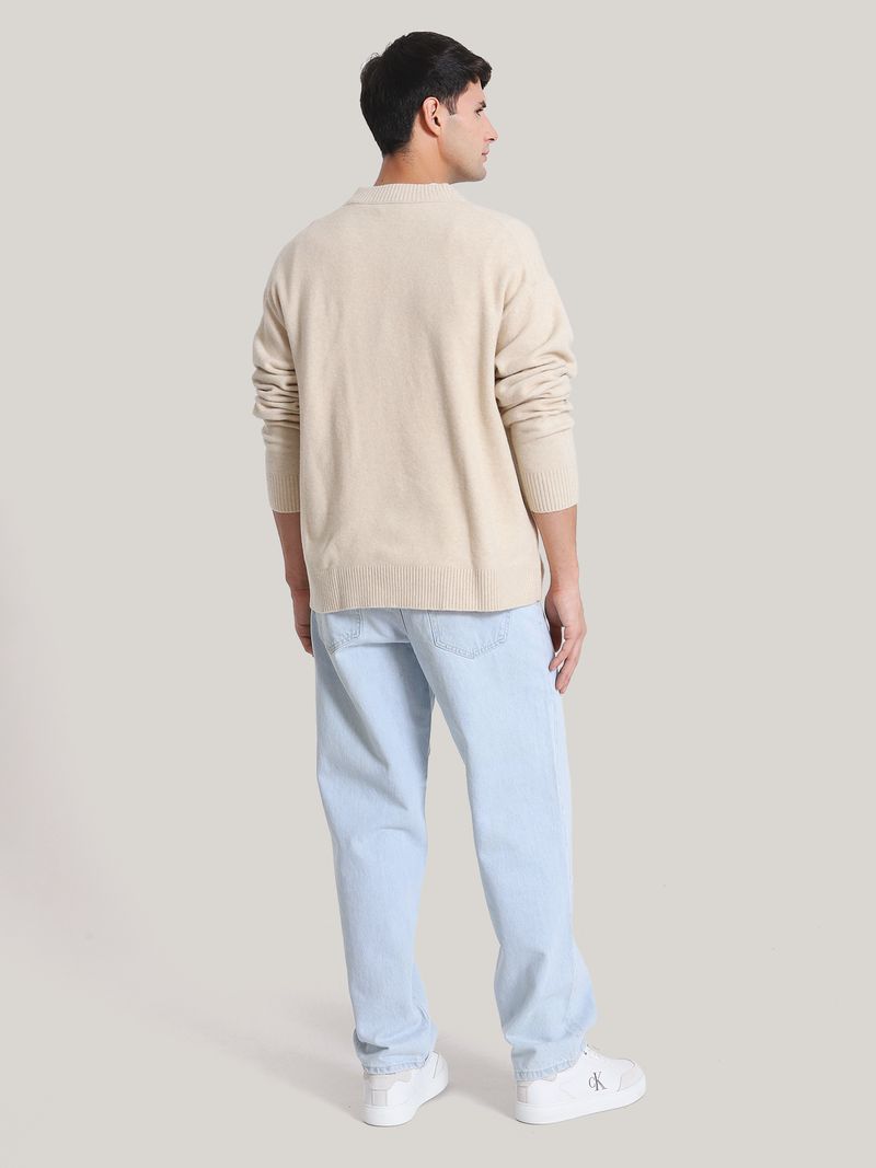 Modelo-con-sweater-beige-Calvin-Klein-de-cuello-en-V-y-jeans-claros