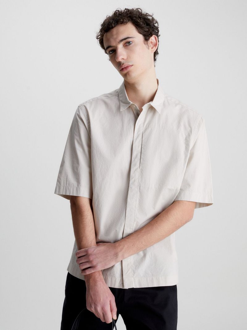 Modelo-con-camisa-beige-Calvin-Klein-y-pantalones-oscuros