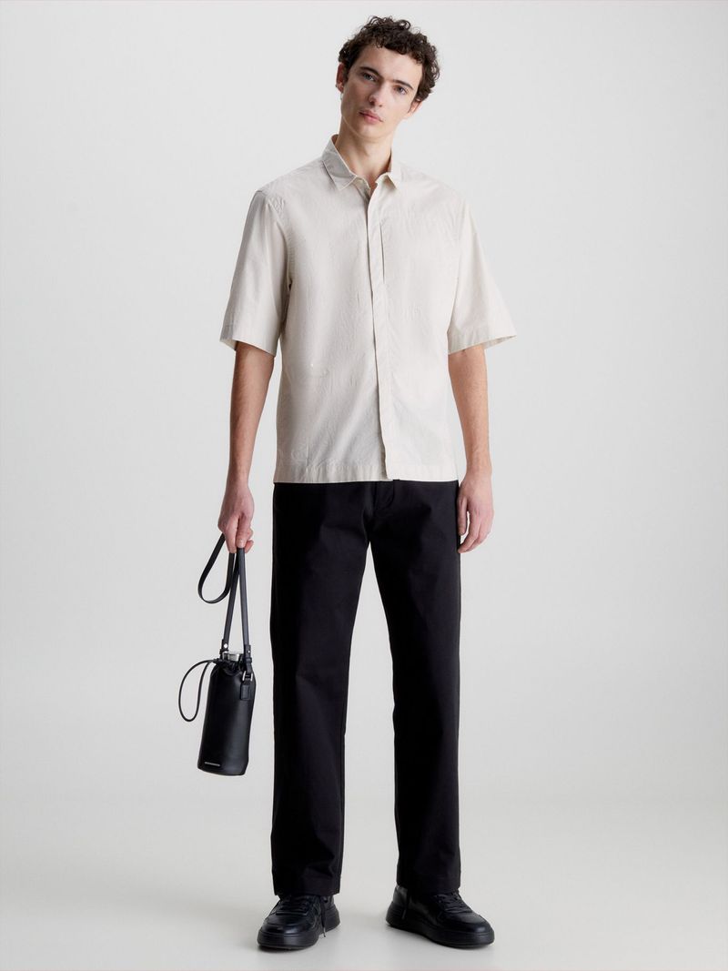 Modelo-con-camisa-beige-Calvin-Klein-y-pantalones-oscuros