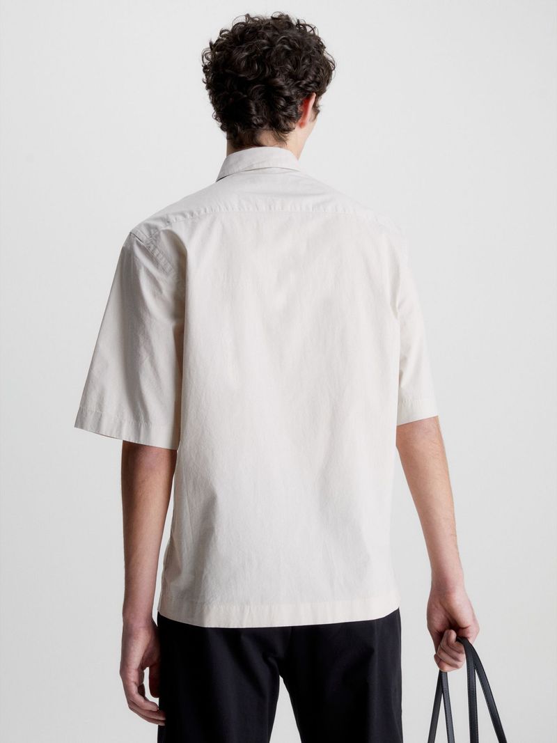 Modelo-con-camisa-beige-Calvin-Klein-y-pantalones-oscuros