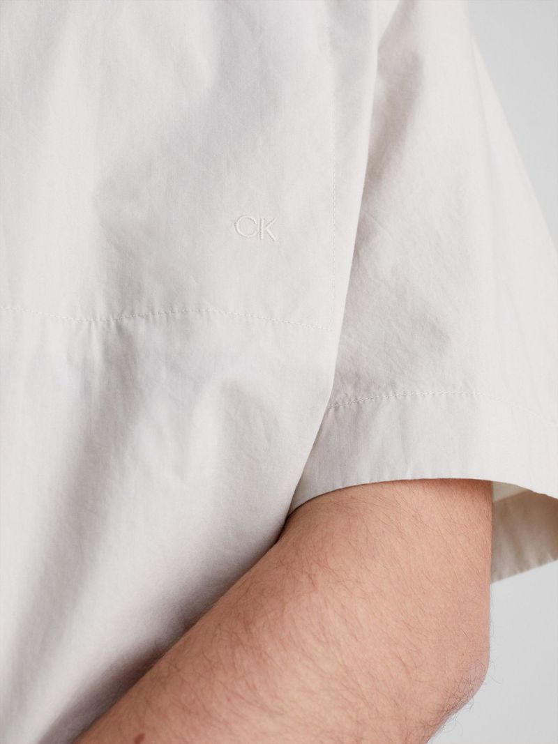Modelo-con-camisa-beige-Calvin-Klein-y-pantalones-oscuros