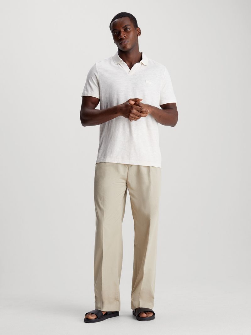 Modelo-vistiendo-polo-blanco-Calvin-Klein-y-pantalones-beige