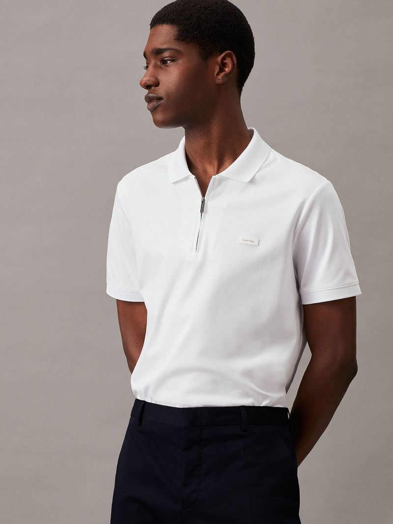 Modelo-con-polera-blanca-de-manga-corta--cierre-en-V-y-cuello-polo--y-pantalones-negros-Calvin-Klein