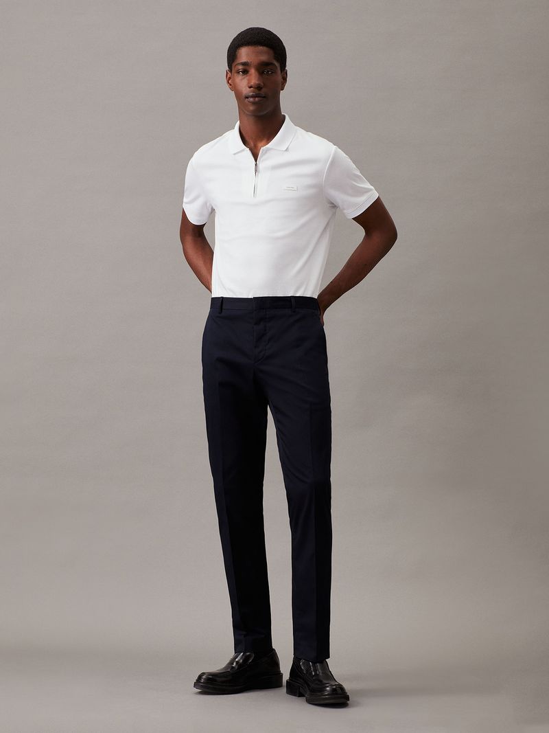 Modelo-con-polera-blanca-de-manga-corta--cierre-en-V-y-cuello-polo--y-pantalones-negros-Calvin-Klein