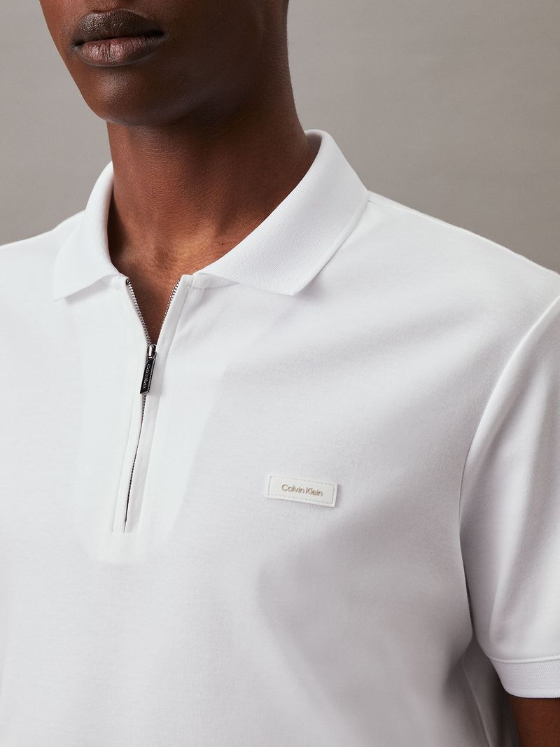 Modelo-con-polera-blanca-de-manga-corta--cierre-en-V-y-cuello-polo--y-pantalones-negros-Calvin-Klein