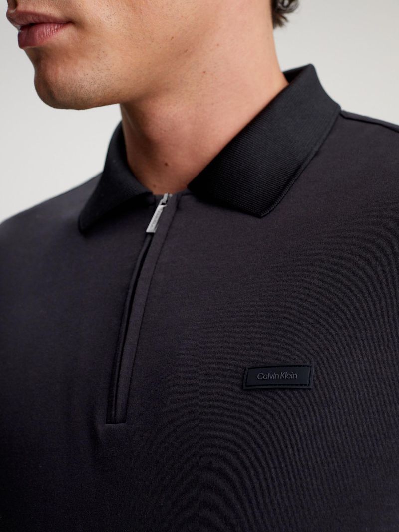 Modelo-con-polo-negro-Calvin-Klein-de-cierre-frontal-y-pantalones-claros