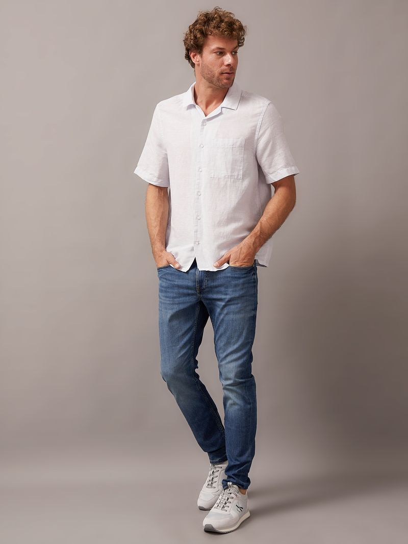 Modelo-con-camisa-blanca-manga-corta-Calvin-Klein-y-jeans-azules