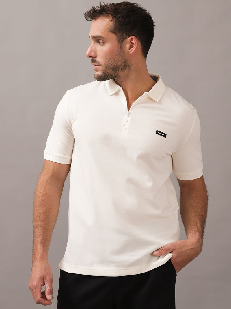 Polera-tipo-polo-color-crema-para-hombre-con-cierre-en-el-cuello-y-detalle-minimalista-de-Calvin-Klein-en-el-pecho.