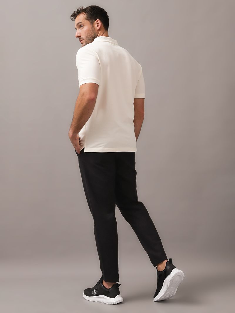 Polera-tipo-polo-color-crema-para-hombre-con-cierre-en-el-cuello-y-detalle-minimalista-de-Calvin-Klein-en-el-pecho.