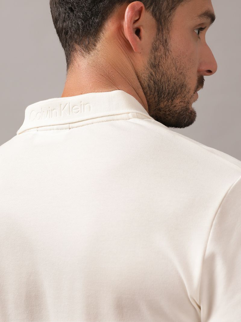 Polera-tipo-polo-color-crema-para-hombre-con-cierre-en-el-cuello-y-detalle-minimalista-de-Calvin-Klein-en-el-pecho.