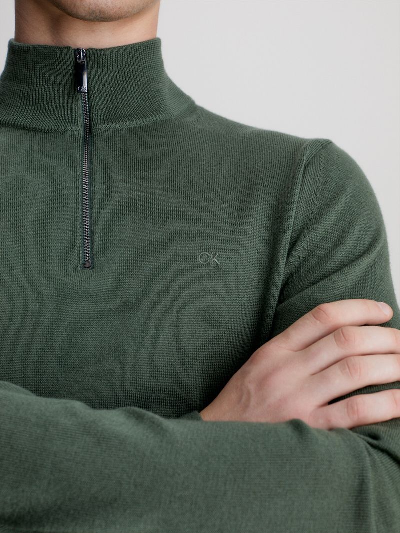 Modelo-con-sweater-verde-oscuro-de-cierre-medio-Calvin-Klein-y-pantalones-negros