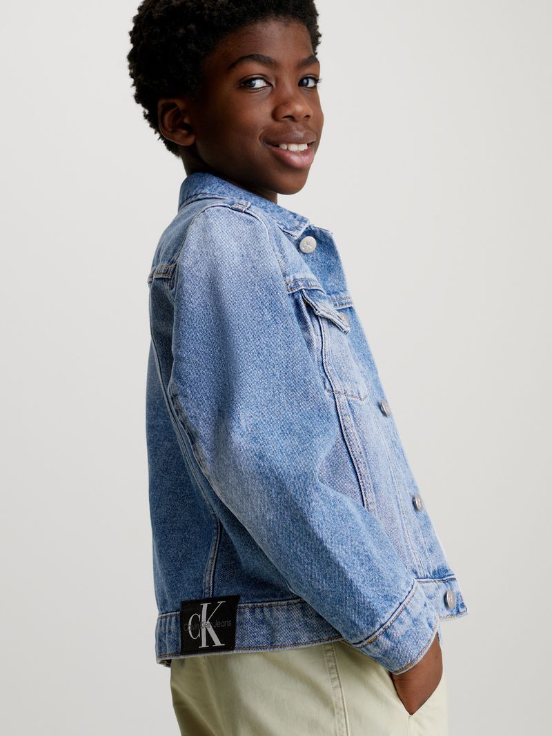 Niño-con-chaqueta-de-mezclilla-azul-Calvin-Klein-polera-blanca-y-pantalones-beige