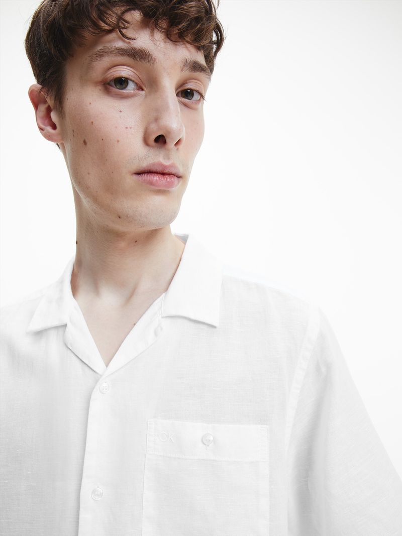 Modelo-con-camisa-manga-corta-blanca-Calvin-Klein-y-pantalones-oscuros