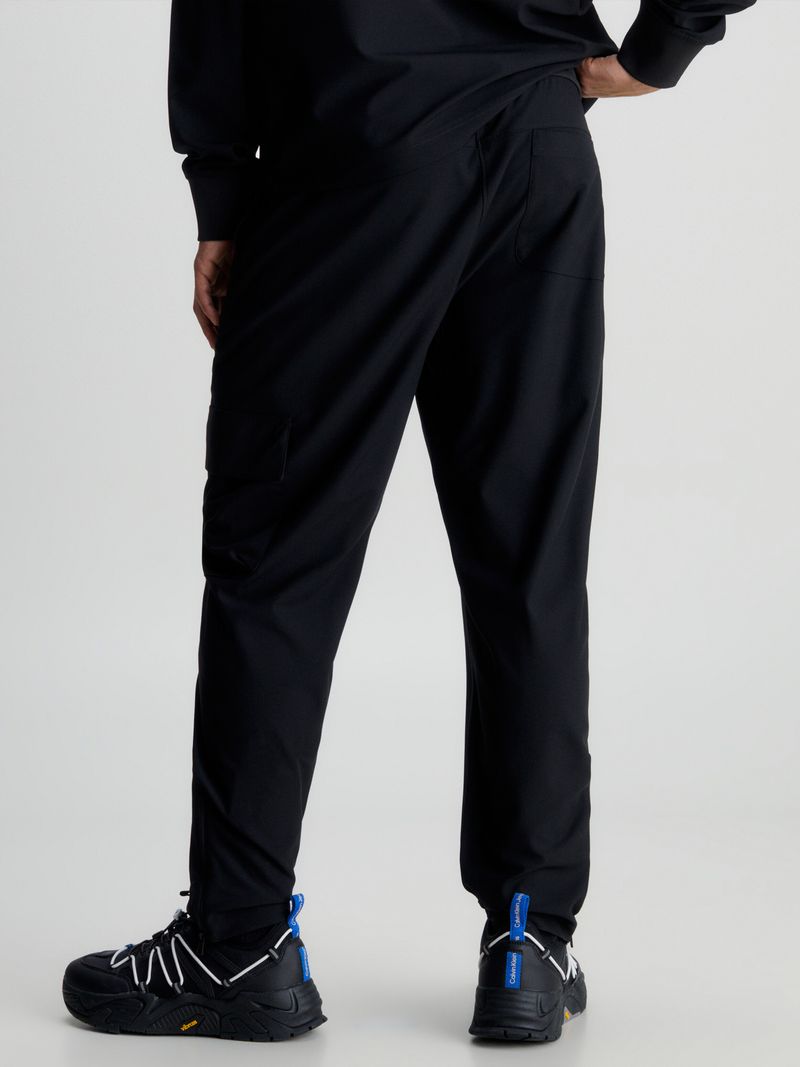 Modelo-usando-pantalon-negro-Calvin-Klein-con-bolsillo-cargo-y-detalles-verdes