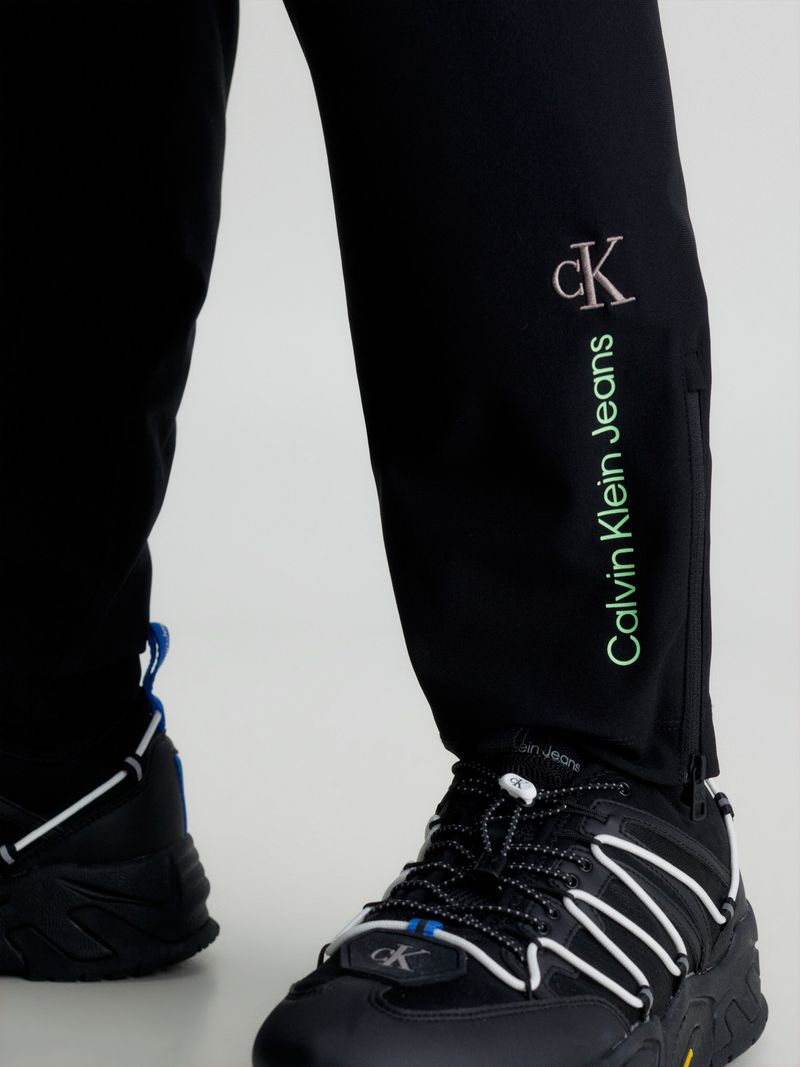 Modelo-usando-pantalon-negro-Calvin-Klein-con-bolsillo-cargo-y-detalles-verdes