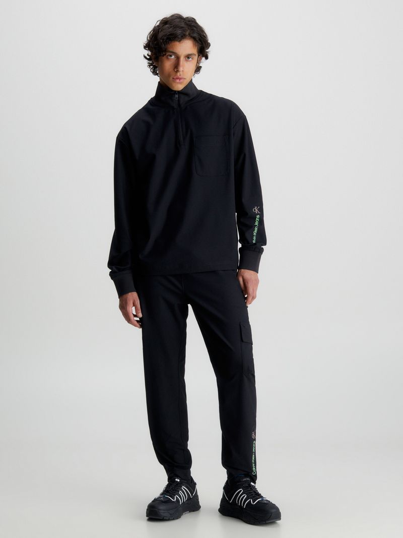 Modelo-usando-pantalon-negro-Calvin-Klein-con-bolsillo-cargo-y-detalles-verdes