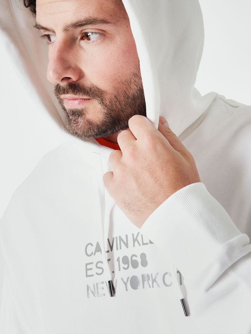 Modelo-con-poleron-blanco-Calvin-Klein-estampado-y-pantalones-oscuros