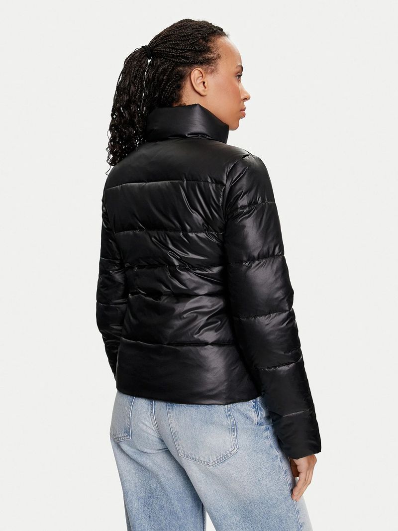 Modelo-con-chaqueta-acolchada-Calvin-Klein-negra-con-cierre-y-logo-bordado-en-el-pecho-combinada-con-jeans-celestes