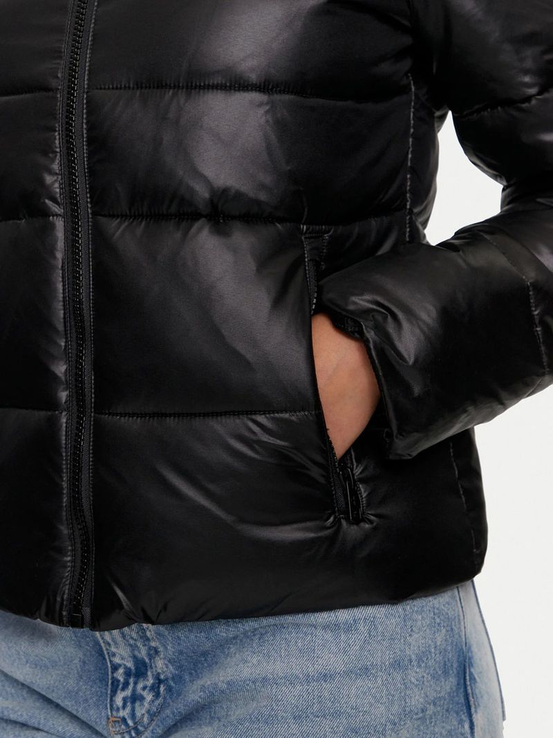 Modelo-con-chaqueta-acolchada-Calvin-Klein-negra-con-cierre-y-logo-bordado-en-el-pecho-combinada-con-jeans-celestes