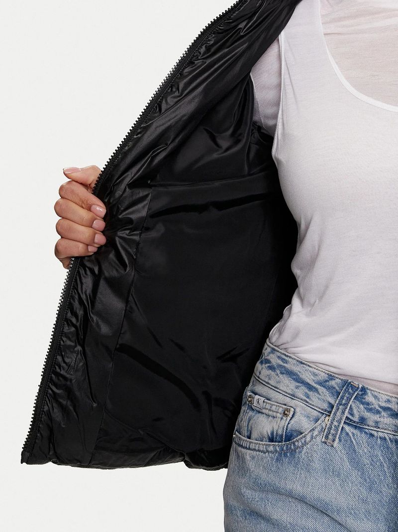 Modelo-con-chaqueta-acolchada-Calvin-Klein-negra-con-cierre-y-logo-bordado-en-el-pecho-combinada-con-jeans-celestes